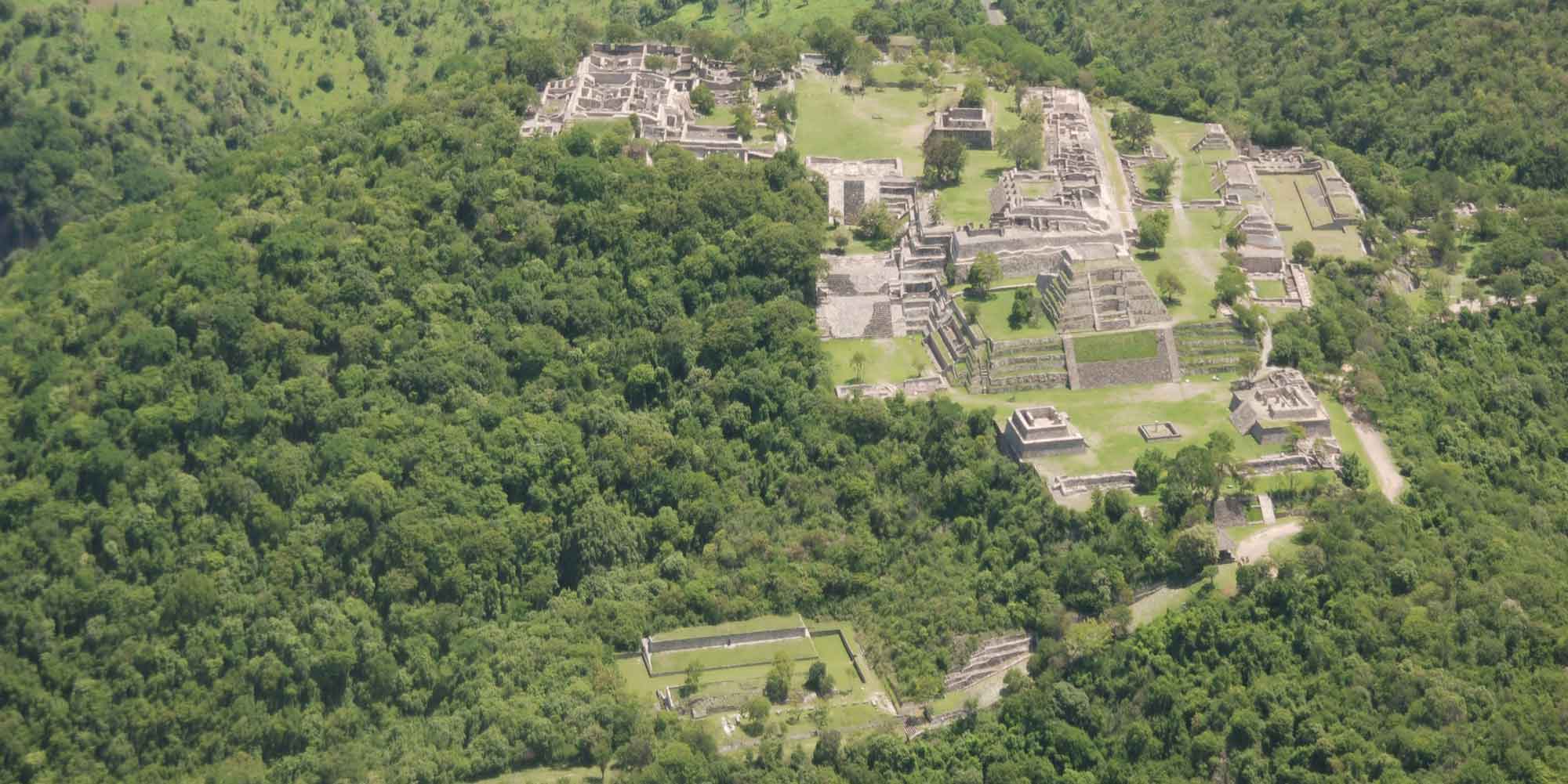 Imagen aérea de la zona arqueológica de Xochicalco, rodeada de vegetación.